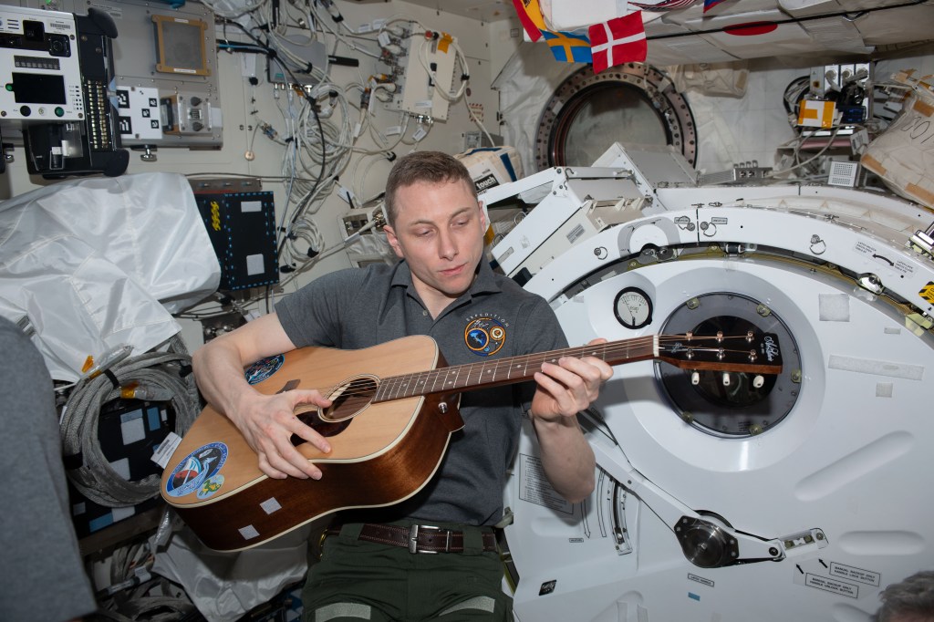 NASA astronaut and Expedition 69 Flight Engineer Woody Hoburg relaxes and plays guitar inside the International Space Station's Kibo laboratory module.