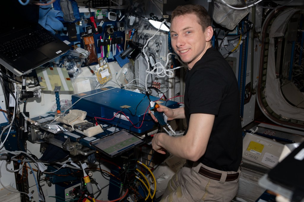 NASA astronaut and Expedition 69 Flight Engineer Woody Hoburg troubleshoots hardware from the the Tranquility module's advanced resistive exercise device (ARED). The ARED is a workout system that mimics free weights on Earth to maintain muscle strength and mass in microgravity.