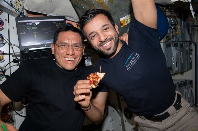 Two Expedition 69 crew members pose for a portrait in the International Space Station's Unity module during the always popular pizza night. From left are, Flight Engineers Frank Rubio from NASA and Sultan Alneyadi from UAE (United Arab Emirates).