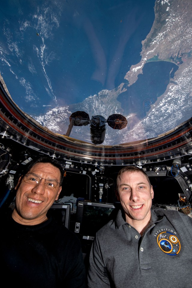Expedition 69 Flight Engineers (from left) Frank Rubio and Woody Hoburg, both from NASA, are pictured in the International Space Station's cupola with Northrop Grumman's Cygnus cargo craft outside in the grips of the Canadarm2 robotic arm. The orbital lab was soaring 260 miles above the Black Sea at the time of this photograph.