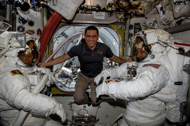 NASA astronaut Frank Rubio (center) assists NASA astronauts (at left and right) Stephen Bowen and Woody Hoburg in their spacesuits before they exit the Quest airlock and begin a spacewalk to install a roll-out solar array on the International Space Station.