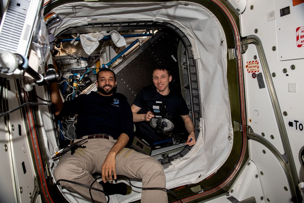 Expedition 69 Flight Engineers (from left) Sultan Alneyadi of UAE (United Arab Emirates) and Woody Hoburg of NASA pose for a portrait inside the vestibule between the Unity module and the Tranquility module during maintenance activities aboard the International Space Station.