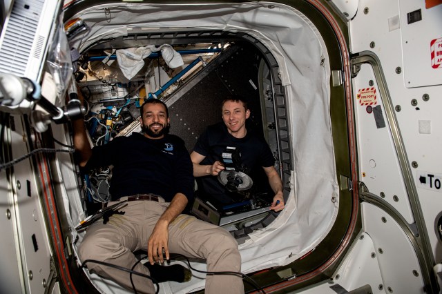 Expedition 69 Flight Engineers (from left) Sultan Alneyadi of UAE (United Arab Emirates) and Woody Hoburg of NASA pose for a portrait inside the vestibule between the Unity module and the Tranquility module during maintenance activities aboard the International Space Station.