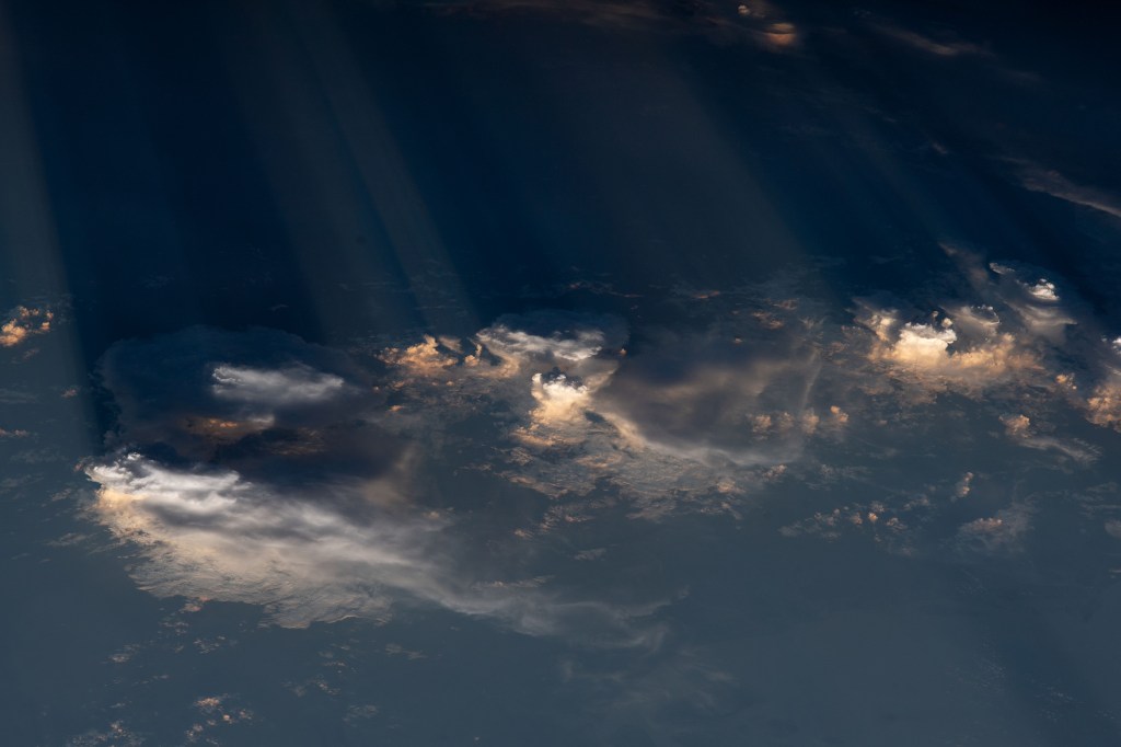 A collection of clouds hangs low over the Middle East as the International Space Station orbited about 260 miles above. Golden reflections from the Sun are dispersed throughout, creating a watercolor-like blend of light gold, white and grey.