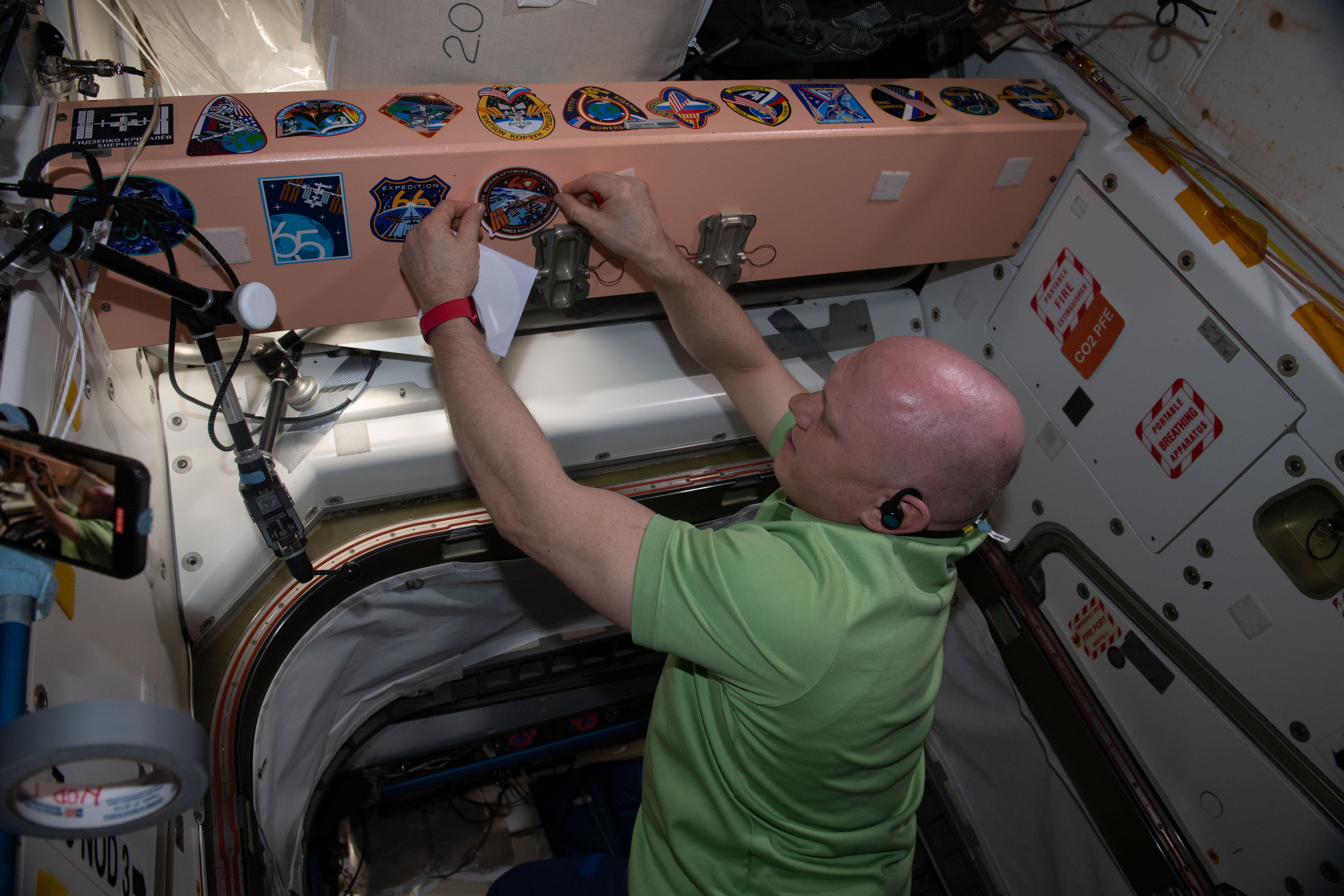 Expedition 67 Commander Oleg Artemyev affixes his mission's insignia sticker to the inside of the International Space Station's Unity module. Artemyev, along with Roscosmos Flight Engineers Denis Matveev and Sergey Korsakov, would depart the orbiting lab on Sept. 29 inside the Soyuz MS-21 crew ship for a parachute-assisted landing in Kazakhstan ending a six-month space research mission.