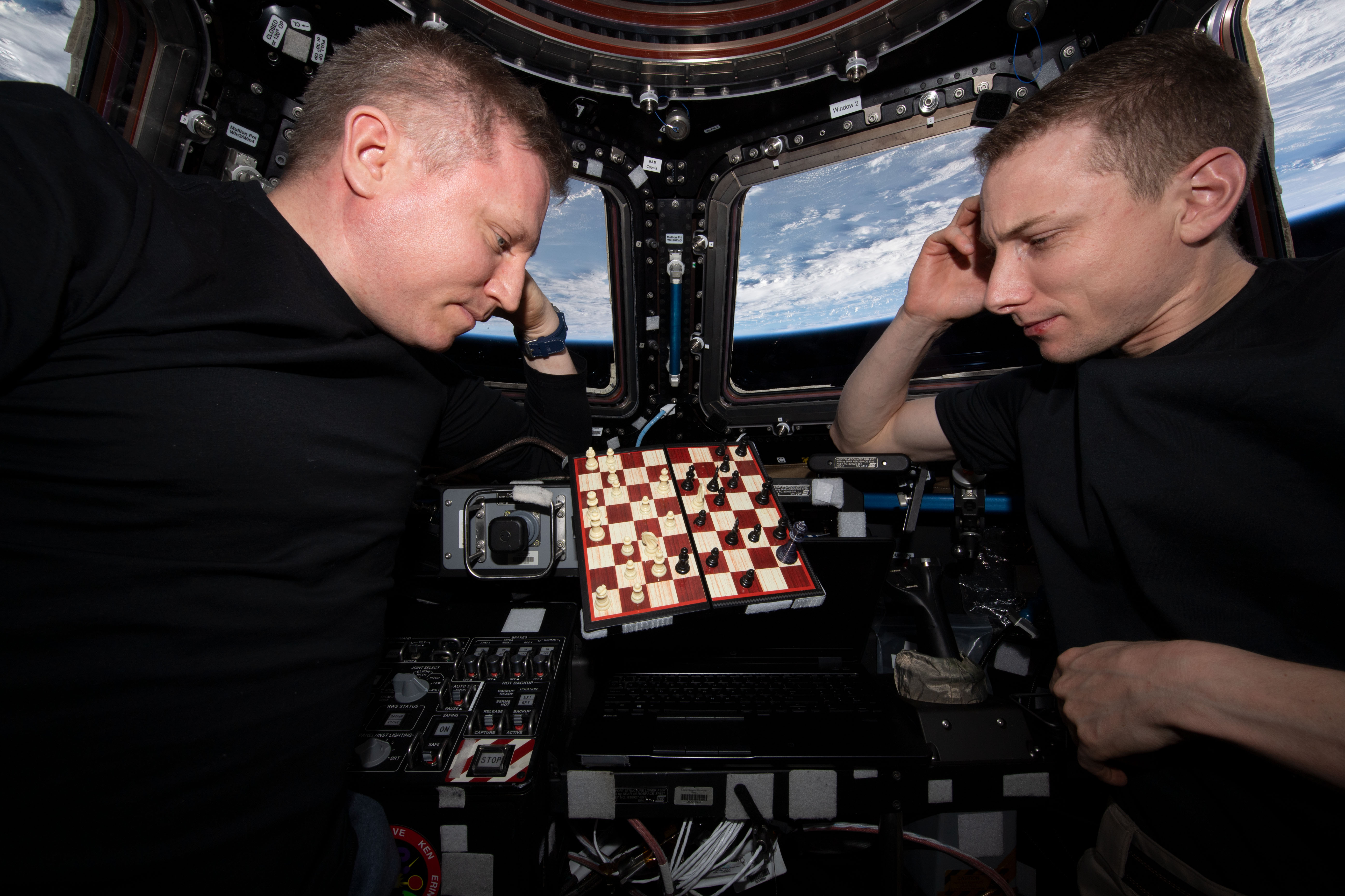 From left, Expedition 69 Commander Sergey Prokopyev of Roscosmos and Flight Engineer Woody Hoburg of NASA each contemplate their next move during an orbital game of chess inside the International Space Station's cupola. The orbital lab was soaring 259 miles above the Colombia-Venezuela border at the time of this photograph.