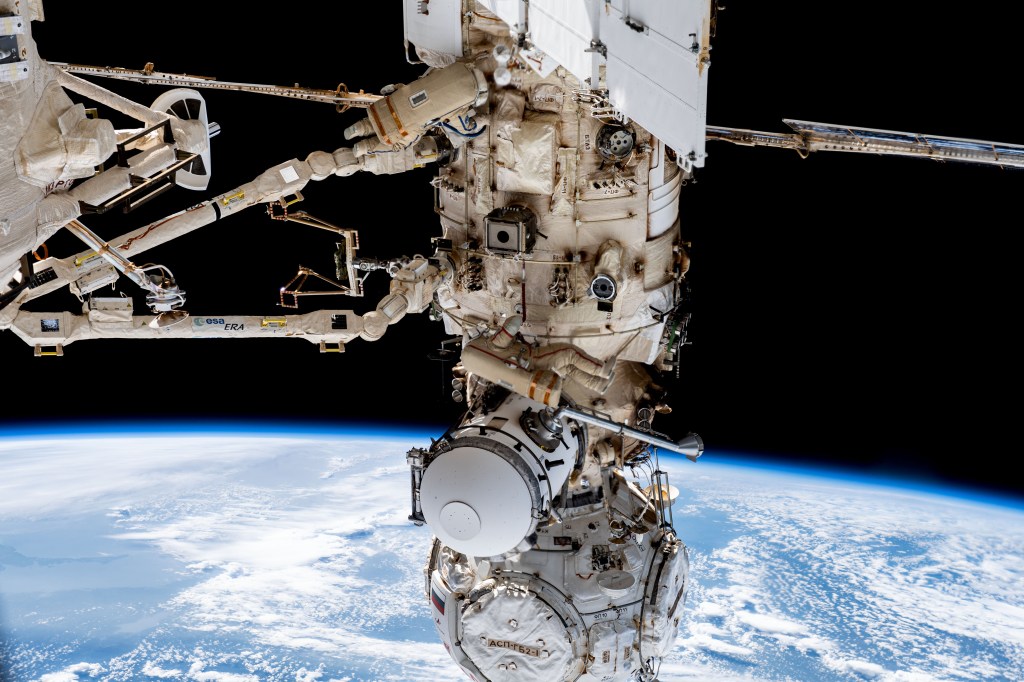 Expedition 69 crew members Dmitri Petelin (top) and Sergey Prokopyev (center), both from Roscosmos, are pictured in their Orlan spacesuits during a six-hour and 35-minute spacewalk to install orbital debris shields and relocate a portable workstation on the International Space Station. The European robotic arm extends from the Nauka science module to which the Prichal module and the Soyuz MS-23 crew ship are attached.