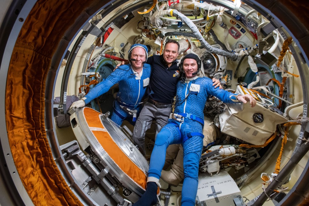 iss067e034957 (April 28, 2021) --- Roscosmos cosmonauts (from left) Oleg Artemyev, Sergey Korsakov and Denis Matveev, are pictured inside the International Space Station's Poisk module. Korsakov had helped Artemyev and Matveev out of their Orlan spacesuits after they had just completed a seven-hour and 42-minute spacewalk to activate the European robotic arm on the Nauka multipurpose laboratory module.