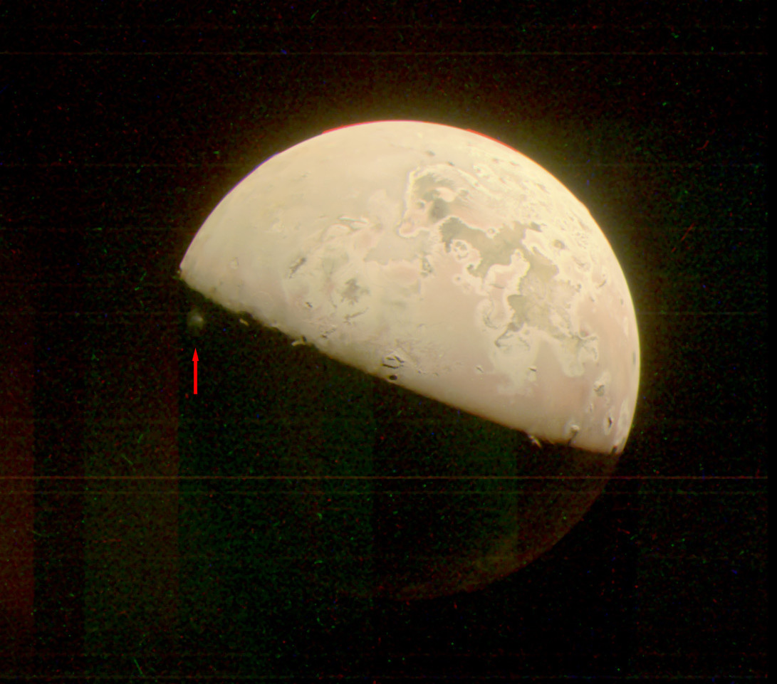 Questa immagine JunoCam della luna di Giove, Io, cattura un pennacchio di materiale espulso dal vulcano (invisibile) Prometeo.  Indicato dalla freccia rossa, il pennacchio è appena visibile nell'oscurità sotto il terminatore (la linea che divide il giorno dalla notte).  L'immagine è stata scattata dalla navicella spaziale Juno della NASA il 15 giugno.