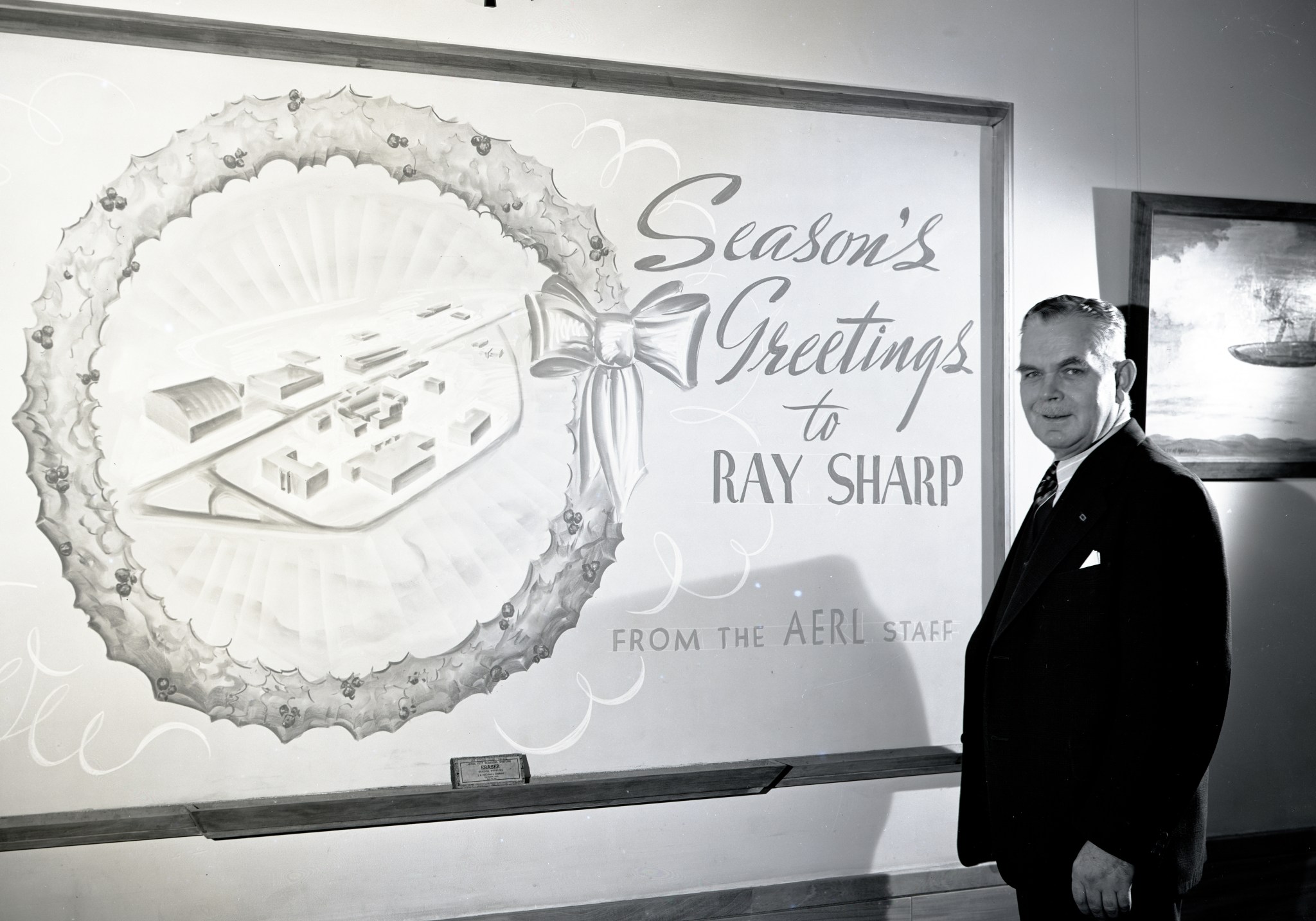 Man standing by chalkboard with holiday message.