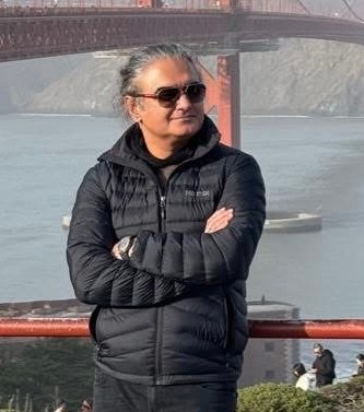 portrait of a man in a black puffer coat, standing on a boat deck with Golden Gate bridge in the background
