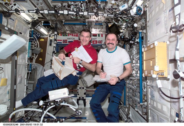 Astronaut James S. Voss (left), Expedition Two flight engineer, unpacks a stowage bag while cosmonaut Yury V. Usachev, Expedition Two mission commander, takes notes in the U.S. Laboratory / Destiny module of the International Space Station (ISS). This image was recorded with a digital still camera.
