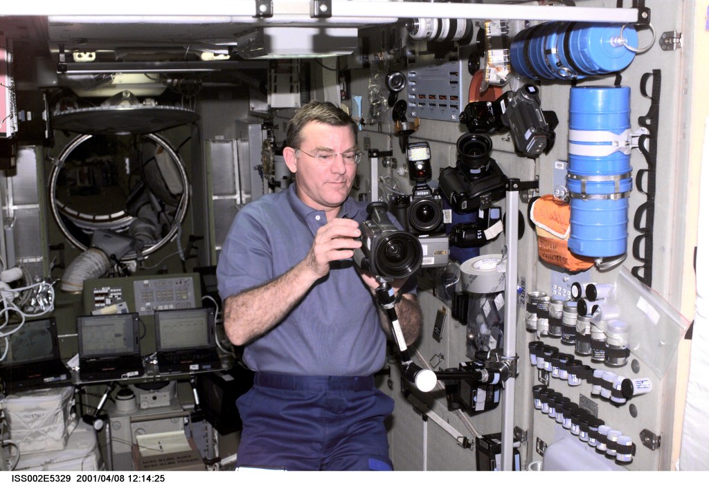 ISS002-E-5329 (08 April 2001) --- Astronaut James S. Voss, Expedition Two flight engineer, sets up a video camera on a mounting bracket in the Zvezda Service Module of the International Space Station (ISS). A 35mm camera and a digital still camera are also visible nearby. This image was recorded with a digital still camera.