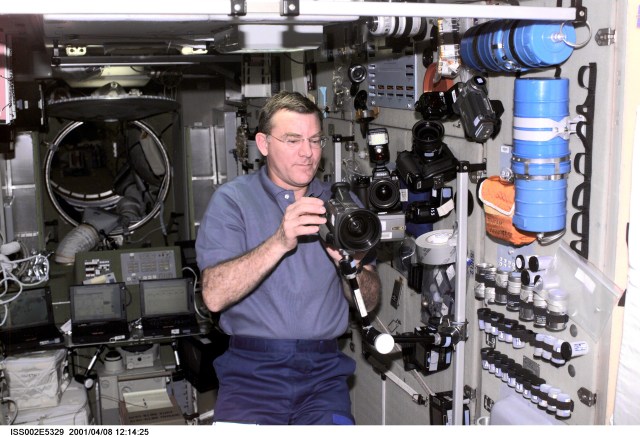 ISS002-E-5329 (08 April 2001) --- Astronaut James S. Voss, Expedition Two flight engineer, sets up a video camera on a mounting bracket in the Zvezda Service Module of the International Space Station (ISS). A 35mm camera and a digital still camera are also visible nearby. This image was recorded with a digital still camera.