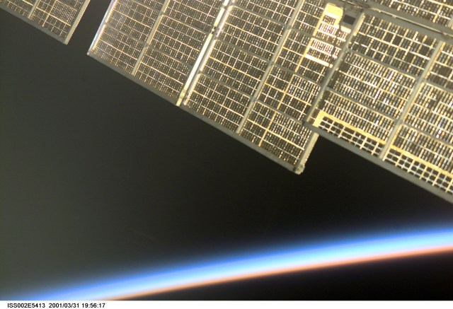 As the sun sets on the Earth's horizon, a golden reflection emanates from the solar array of the Zvezda / Service Module of the International Space Station (ISS). An Expedition Two crewmember took this unusual photograph with a digital still camera.