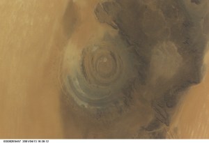 The "bull's-eye" of the Richat Structure adds interest to the barren Gres de Chinguetti Plateau in central Mauritania in northwest Africa. It represents domally uplifted, layered (sedimentary) rocks that have been eroded by water and wind into the present shape. The 25-mile-wide structure is a 300-foot-deep landmark that has caught the eye of many an astronaut in Earth orbit. Image number ISS002-E-5693 shows the same feature six days later. The image was recorded with a digital still camera.