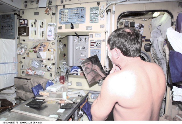 Yury V. Usachev of Rosaviakosmos, Expedtion Two mission commander, shaves with an electric razor in the Zvezda Service Module. The image was taken with a digital still camera.