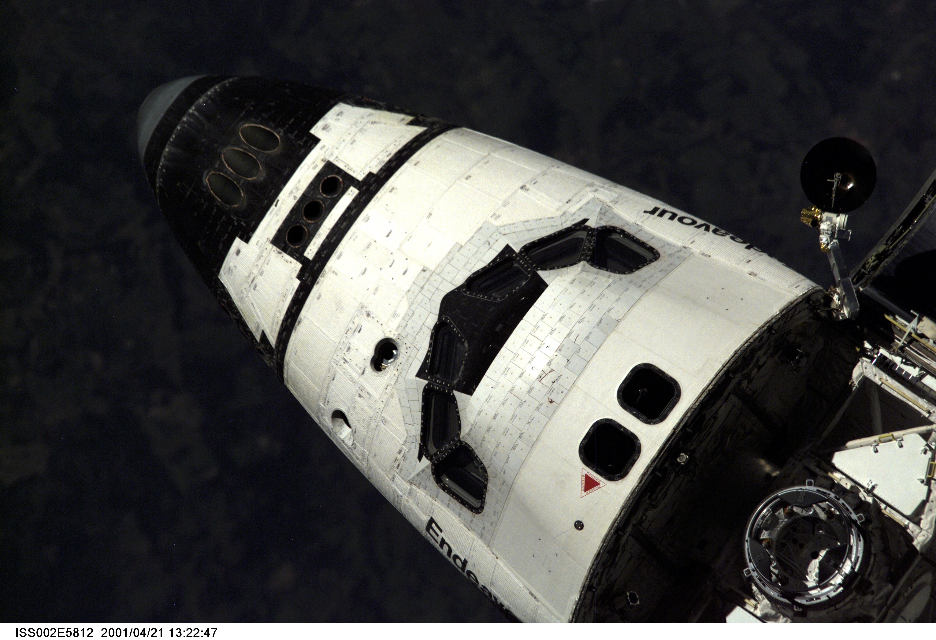The cabin and part of the forward cargo bay, including the Ku-band antenna and common berthing mechanism (CBM), are visible as the Space Shuttle Endeavour, with six astronauts and a cosmonaut onboard, approaches the International Space Station (ISS) for an April 21 docking. The photo was taken with a digital still camera by one of the three Expedition Two crew members onboard the Station.