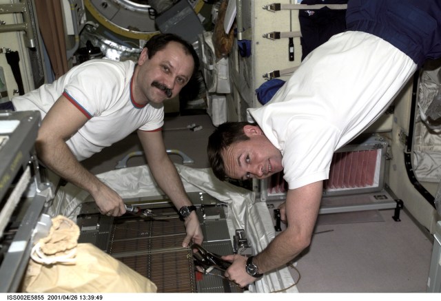 Two cosmonauts from Rosaviakosmos, Yury V. Usachev (left), Expedtion Two mission commander, and Yuri V. Lonchakov, STS-100 mission specialist, work on the Treadmill Vibration Isolation System (TVIS) in the Zvezda Service Module during the STS-100 visit to the International Space Station (ISS). The image was taken with a digital still camera.