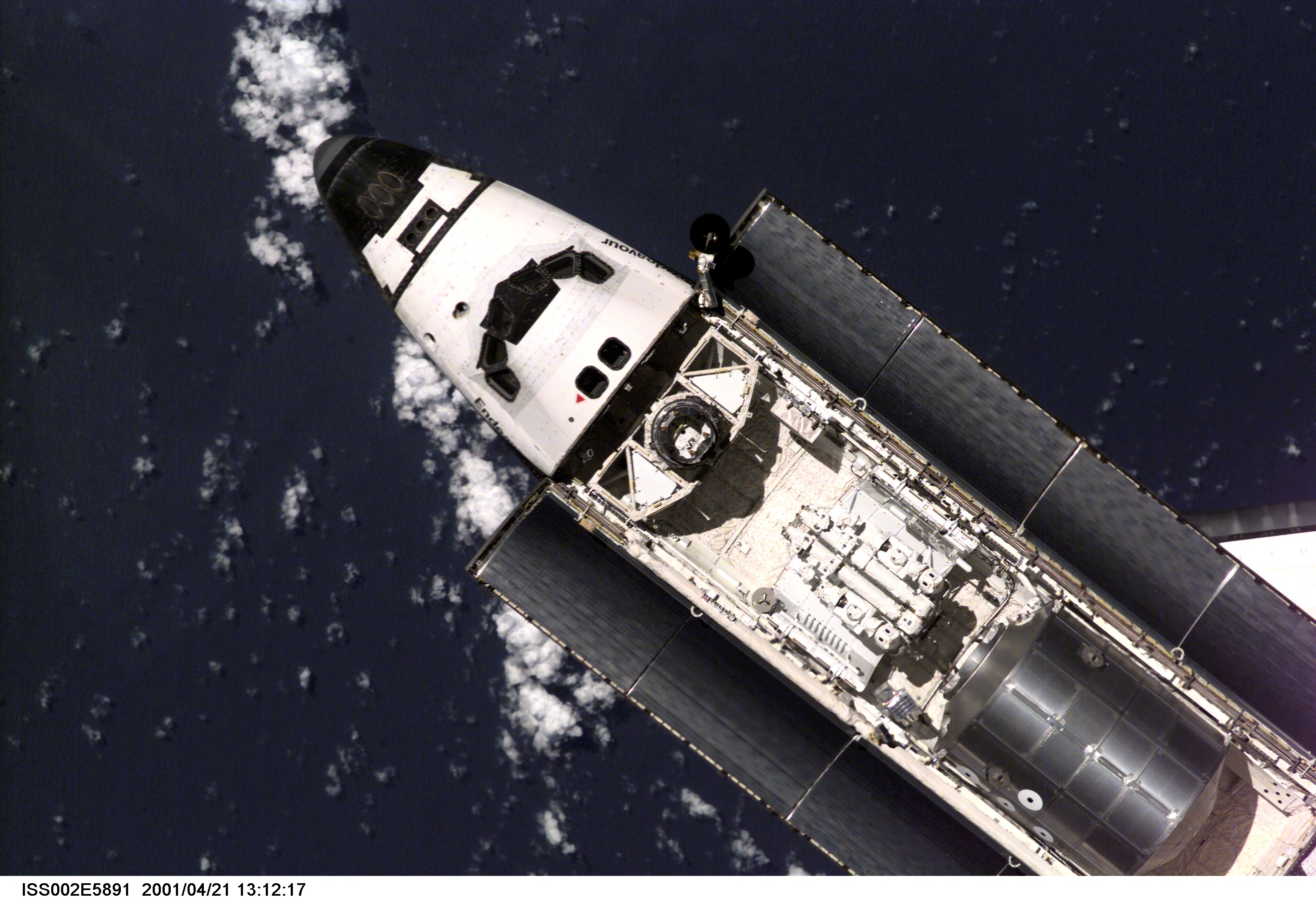 A distant view of the Space Shuttle Endeavour preparing to dock with the International Space Station (ISS) during the STS-100 mission. The STS-100 crewmembers are delivering the Canadarm2, Space Station Remote Manipulator System (SSRMS), and equipment stowed in the Multipurpose Logistics Module (MPLM) Raphaello to the ISS which are visible in Endeavour's payload bay. The image was taken with a digital still camera.