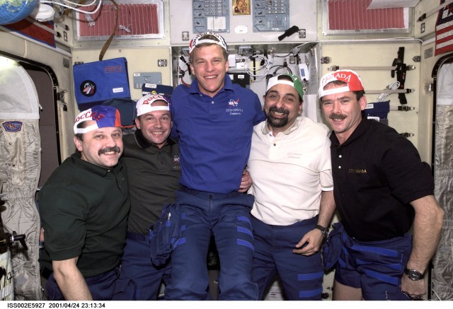 Yury V. Usachev, Expedition Two mission commander; Yuri V. Lonchakov, STS-100 mission specialist; Scott E. Parazynski, STS-100 mission specialist; Umberto Guidoni, STS-100 mission specialist; and Chris A. Hadfield, STS-100 mission specialist, pose in the Zvezda Service Module wearing baseball caps representing their home countries, showing the true flavor of the International Space Station (ISS). Usachev and Lonchakov represent Rosaviakosmos, Guidoni represents the European Space Agency (ESA), Parazynski represents NASA, and Hadfield represents the Canadian Space Agency (CSA). The image was taken with a digital still camera.