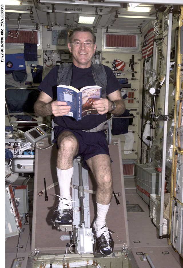 James S. Voss, Expedition Two flight engineer, reads the book "The Last of the Mohicans" while exercising on the cycle ergometer in the Zvezda Service Module. The image was taken with a digital still camera.