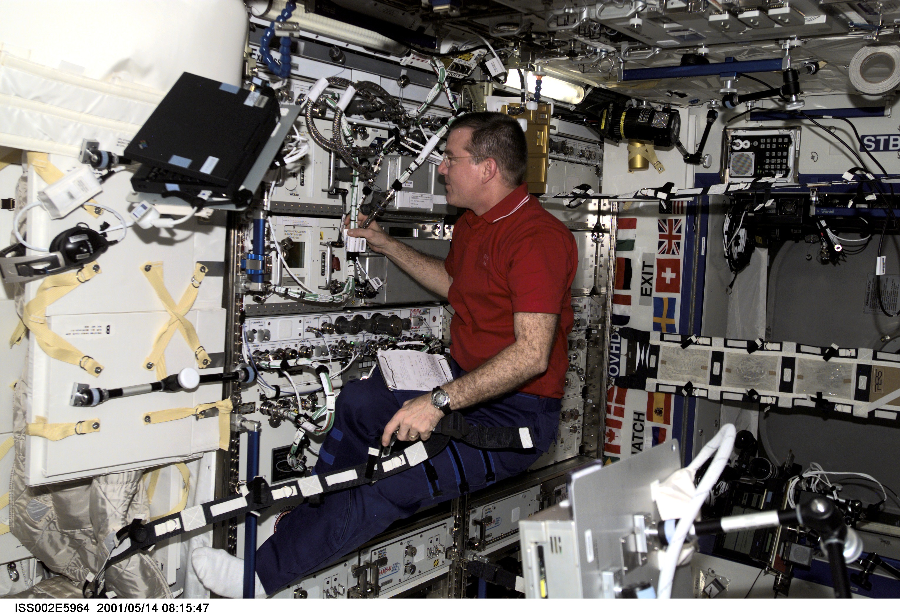 James S. Voss, Expedition Two flight engineer, works with a series of cables in the U.S. Laboratory. The image was taken with a digital still camera.