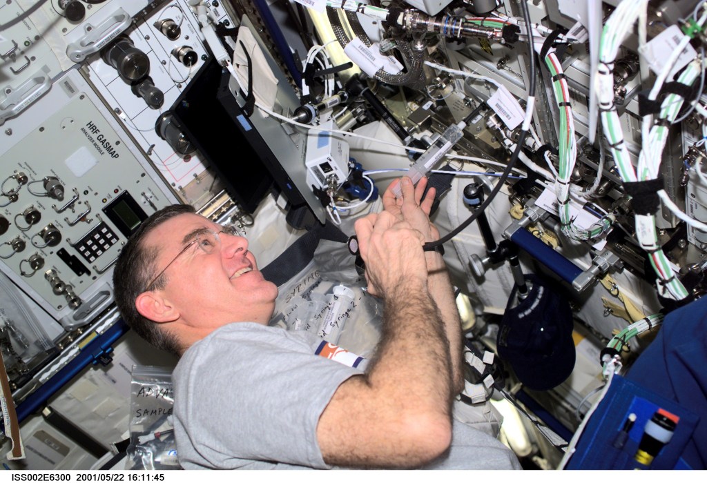 James S. Voss, Expedition Two flight engineer, works with the Advanced Astro Culture (ADVASC) Condensate Fluid Syringe at the ADVASC Growth Chamber in the U.S. Laboratory. The image was taken with a digital still camera.