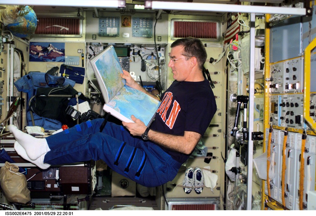James S. Voss, Expedition Two flight engineer, looks over an atlas in the Zvezda Service Module. The image was taken with a digital still camera.