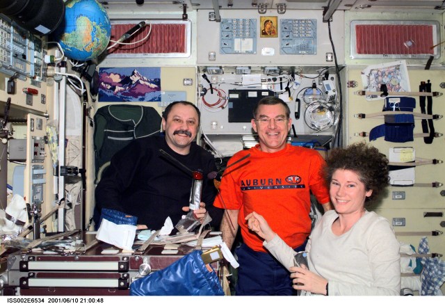 Expedition Two crewmembers Yury V. Usachev (left), mission commander, James S. Voss, flight engineer, and Susan J. Helms, flight engineer, share a dessert in the Zvezda Service Module. Usachev represents Rosaviakosmos. The image was recorded with a digital still camera.