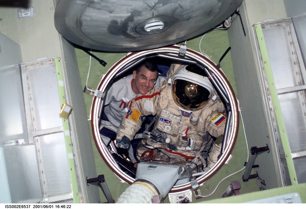 Astronaut James S. Voss, Expedition Two flight engineer, moves an Orlan spacesuit through the forward hatch of the Zvezda Service Module. The image was recorded with a digital still camera.