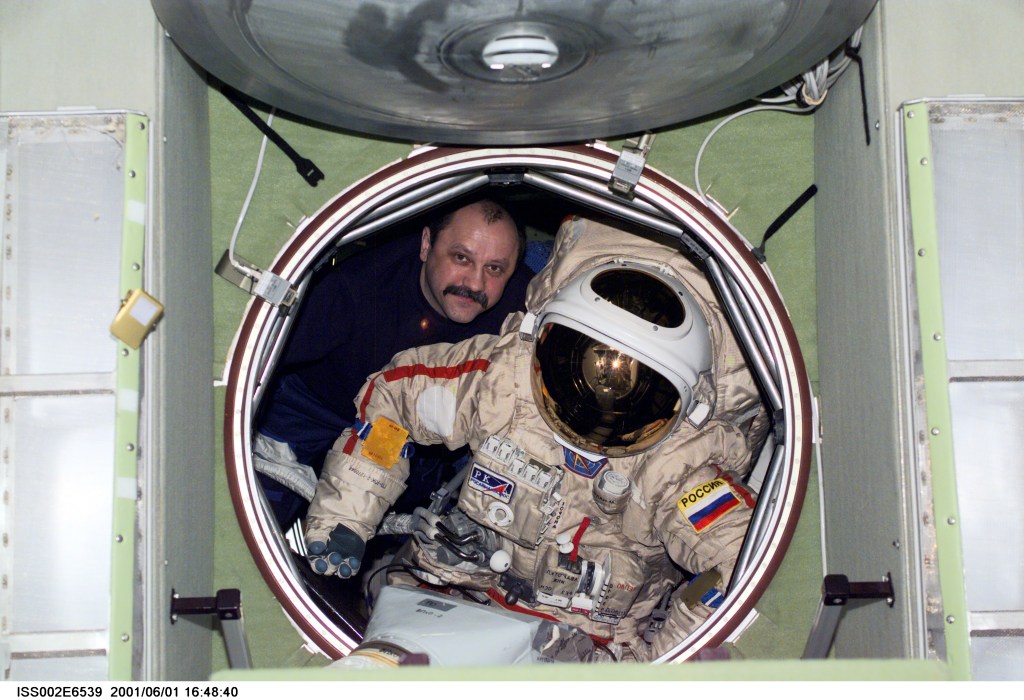 Cosmonaut Yury V. Usachev of Rosaviakosmos, Expedition Two mission commander, moves an Orlan spacesuit through the forward hatch of the Zvezda Service Module. The image was recorded with a digital still camera.