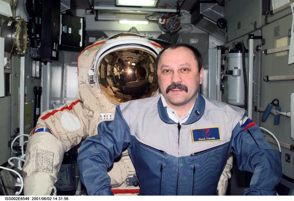Cosmonaut Yury V. Usachev of Rosaviakosmos, Expedition Two mission commander, mimics the natural stance of an empty Orlan spacesuit in the Zvezda Service Module. This image was taken with a digital still camera.