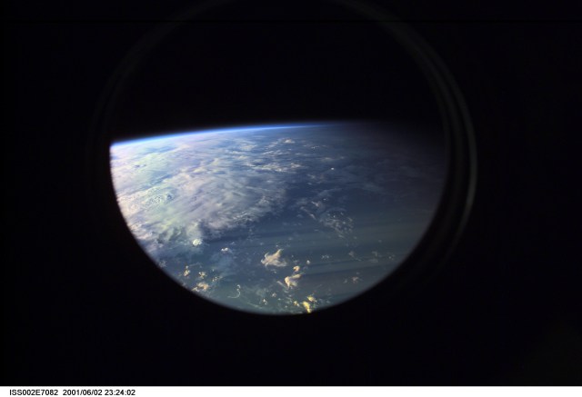 Earth's limb at sunset as photographed by one of the Expedition Two crew members with a digital still camera aimed through the nadir window of the U.S. laboratory Destiny. Beneath the limb, a large mass of clouds fills the window.