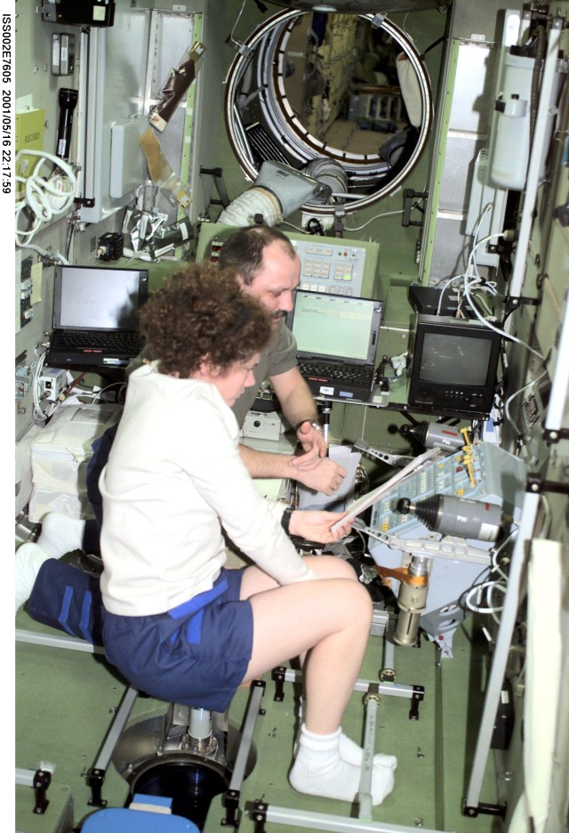 Susan J. Helms, flight engineer, and Yury V. Usachev of Rosaviakosmos, mission commander, read over procedures at the computer workstation in the Zvezda Service Module during the Expedition Two mission. The image was taken with a digital still camera.