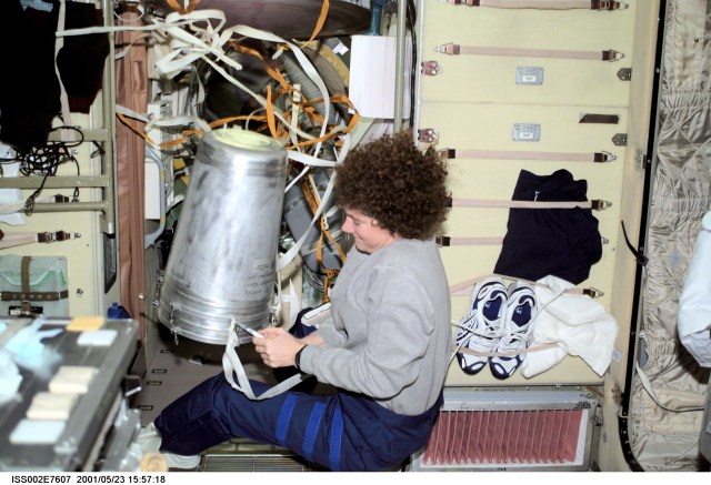 Susan J. Helms, Expedition Two flight engineer, works with a strap on a water container in the Zvezda Service Module. The image was taken with a digital still camera.