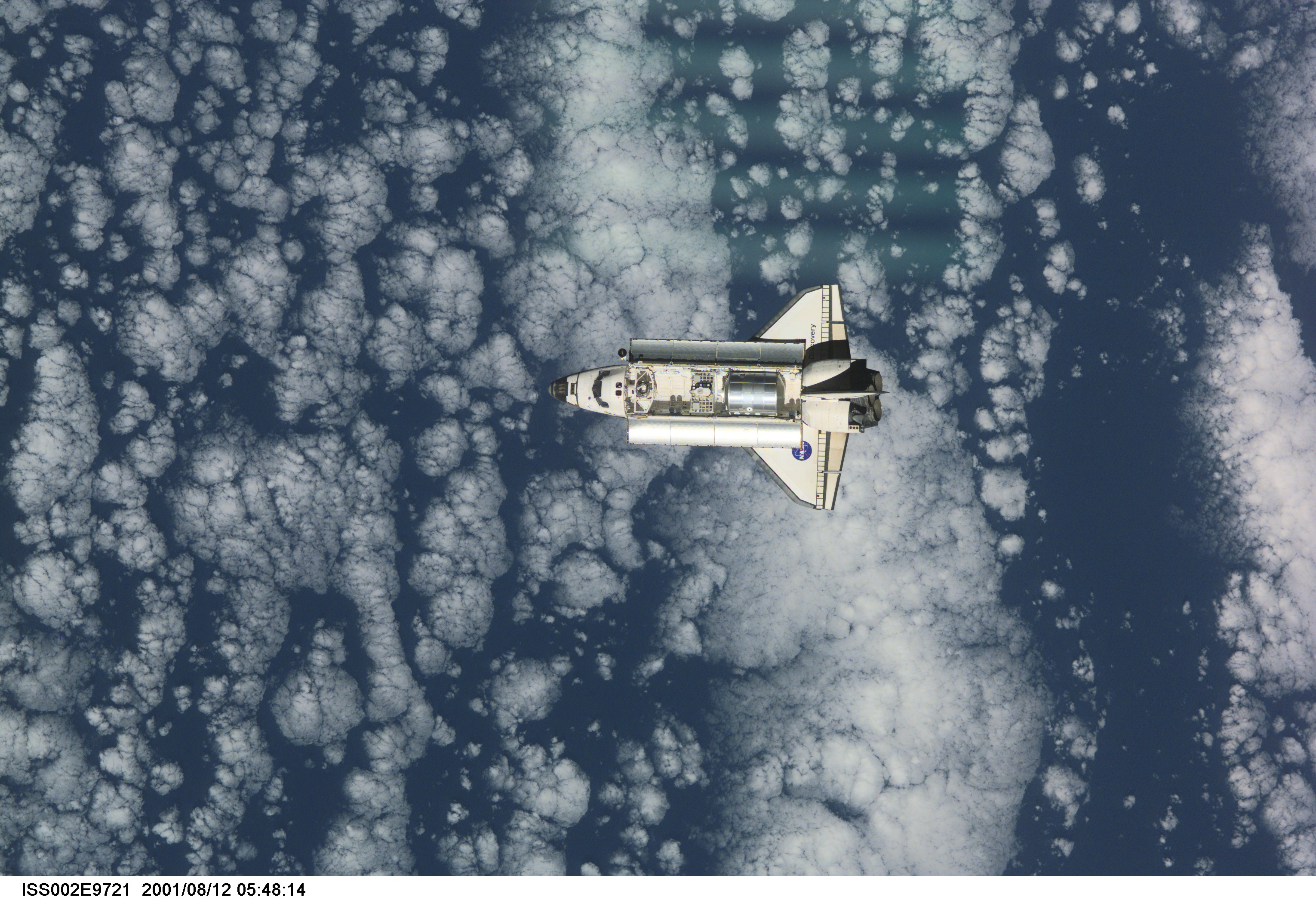 View of the Space Shuttle Discovery as it approaches the International Space Station (ISS) during the STS-105 mission. Aboard Discovery are the members of the Expedition Three crew - Frank L. Culbertson, Jr., mission commander, and cosmonauts Vladimir N. Dezhurov and Mikhail Tyurin, flight engineers - who will be replacing the Expedition Two crew that has been living on the ISS for the past five months. Visible in the payload bay of Discovery are the Multipurpose Logistics Module (MPLM) Leonardo which stores various supplies and experiments to be transferred into the ISS; and the Integrated Cargo Carrier (ICC), which carries the Early Ammonia Servicer (EAS) and two Materials International Space Station Experiment (MISSE) containers. This image was taken with a digital still camera.