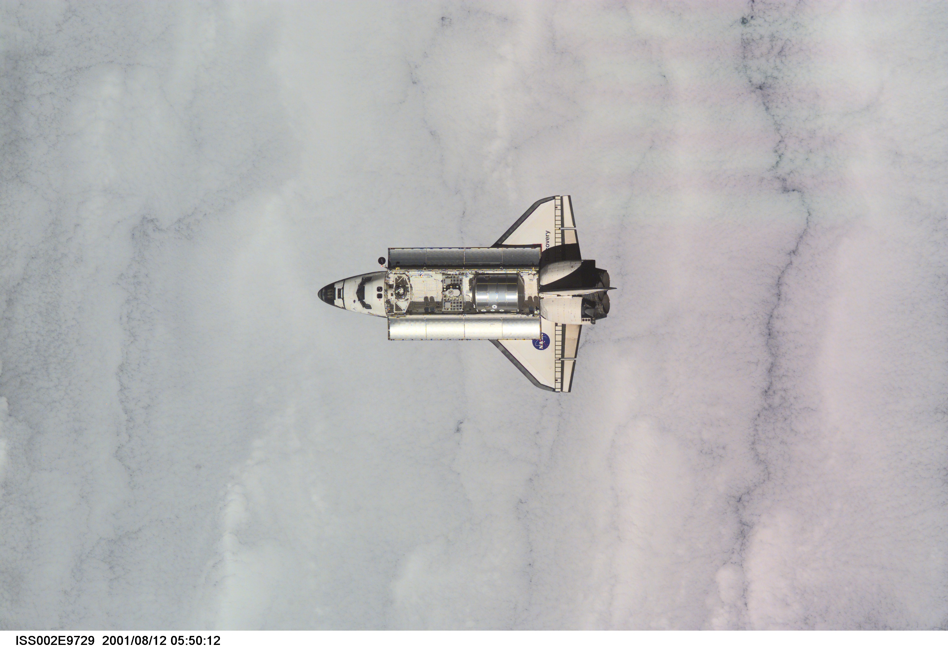 View of the Space Shuttle Discovery as it approaches the International Space Station (ISS) during the STS-105 mission. Aboard Discovery are the members of the Expedition Three crew - Frank L. Culbertson, Jr., mission commander, and cosmonauts Vladimir N. Dezhurov and Mikhail Tyurin, flight engineers - who will be replacing the Expedition Two crew that has been living on the ISS for the past five months. Visible in the payload bay of Discovery are the Multipurpose Logistics Module (MPLM) Leonardo, which stores various supplies and experiments to be transferred into the ISS; and the Integrated Cargo Carrier (ICC) which carries the Early Ammonia Servicer (EAS) and two Materials International Space Station Experiment (MISSE) containers. This image was taken with a digital still camera.