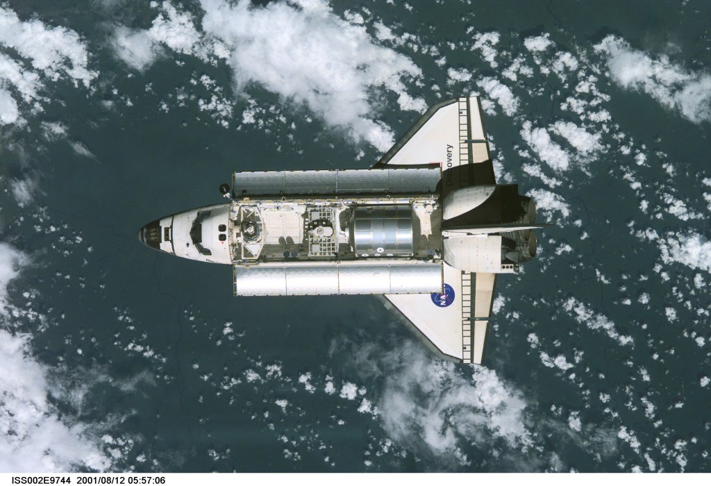View of the Space Shuttle Discovery as it approaches the International Space Station (ISS) during the STS-105 mission. Aboard Discovery are the members of the Expedition Three crew - Frank L. Culbertson, Jr., mission commander, and cosmonauts Vladimir N. Dezhurov and Mikhail Tyurin, flight engineers - who will be replacing the Expedition Two crew that has been living on the ISS for the past five months. Visible in the payload bay of Discovery are the Multipurpose Logistics Module (MPLM) Leonardo, which stores various supplies and experiments to be transferred into the ISS; and the Integrated Cargo Carrier (ICC) which carries the Early Ammonia Servicer (EAS) and two Materials International Space Station Experiment (MISSE) containers. This image was taken with a digital still camera.