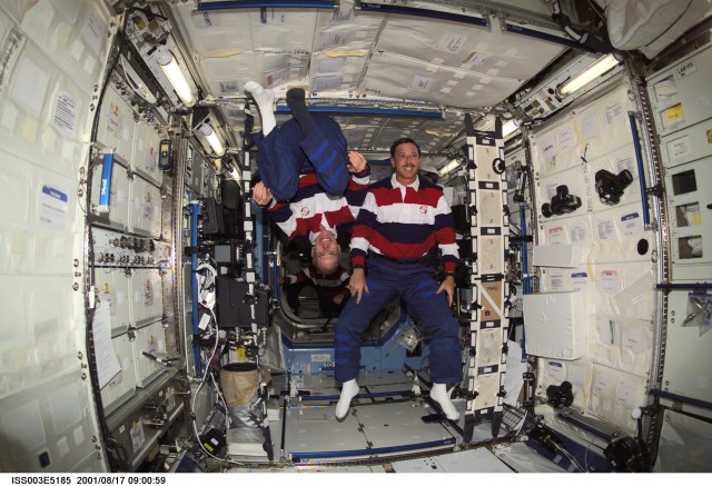 Astronauts Daniel T. Barry (left), STS-105 mission specialist, and Scott J. Horowitz, commander, pause from their daily activities to pose for this photo in the Destiny laboratory while visiting the International Space Station (ISS). This image was taken with a digital still camera.