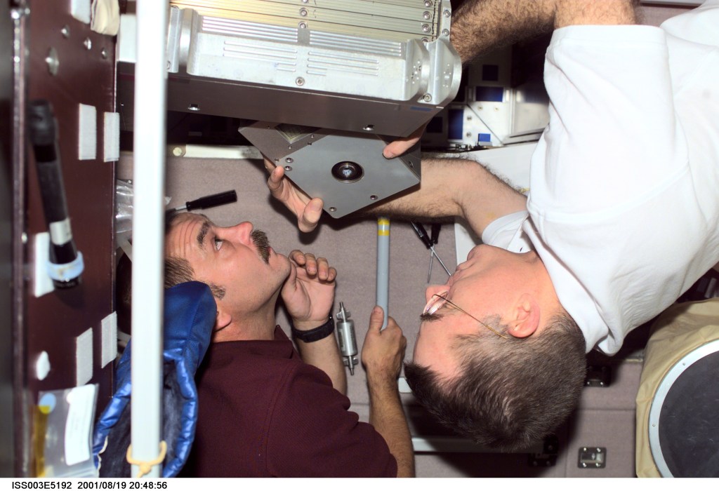 Cosmonaut Mikhail Tyurin (left), Expedition Three flight engineer representing Rosaviakosmos, and astronaut James S. Voss, Expedition Two flight engineer, perform maintenance in the Zvezda Service Module on the International Space Station (ISS). This image was taken with a digital still camera.