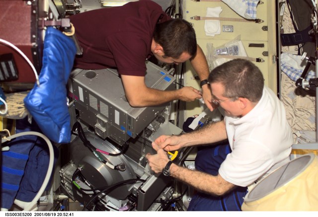 Cosmonaut Mikhail Tyurin (left), Expedition Three flight engineer representing Rosaviakosmos, and astronaut James S. Voss, Expedition Two flight engineer, perform maintenance in the Zvezda Service Module on the International Space Station (ISS). This image was taken with a digital still camera.
