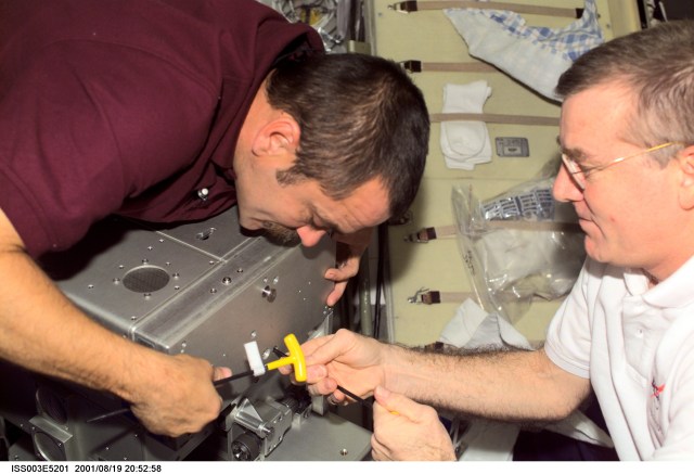 Cosmonaut Mikhail Tyurin (left), Expedition Three flight engineer representing Rosaviakosmos, and astronaut James S. Voss, Expedition Two flight engineer, perform maintenance in the Zvezda Service Module on the International Space Station (ISS). This image was taken with a digital still camera.