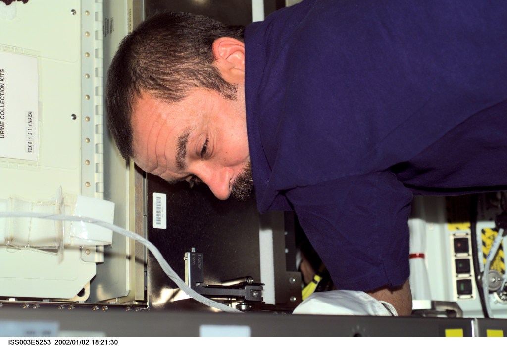 Cosmonaut Mikhail Tyurin, Expedition Three flight engineer representing Rosaviakosmos, works with cables under a panel in the Destiny laboratory on the International Space Station (ISS). This image was taken with a digital still camera.