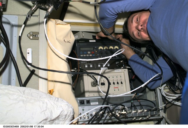 Cosmonaut Vladimir Dezhurov of Rosaviakosmos, Expedition Three flight engineer, works on electronic equipment behind a panel in the Zvezda Service Module. Please note: The date identifiers on some frames are not accurate due to a technical problem with one of the Expedition Three cameras. When a specific date is given in the text or description portion, it is correct.