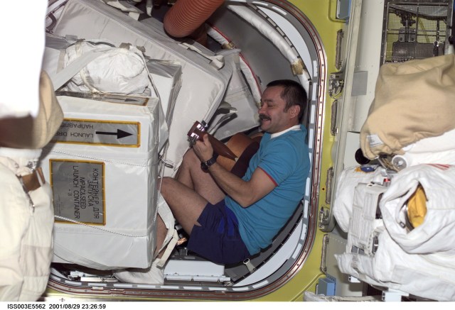 Cosmonaut Mikhail Tyurin of Rosaviakosmos, Expedition Three flight engineer, plays a guitar among stowage bags in the hatch area of the Quest Airlock.