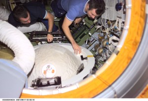 Cosmonaut Mikhail Tyurin (left) and cosmonaut Vladimir Dezhurov, Expedition Three flight engineers, remove the docking probe in the Zvezda Service Module's pressurized adapter. The docking probe successfully guided the arrival of the Russian- built Pirs docking compartment to the International Space Station (ISS). Tyurin and Dezhurov represent Rosaviakosmos.