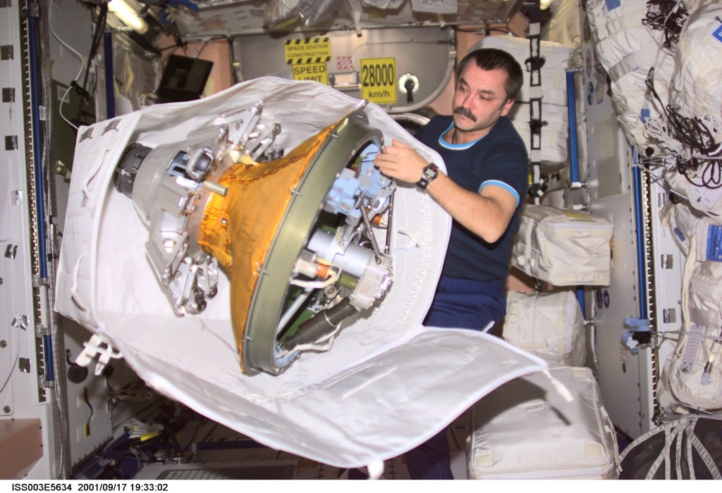 Cosmonaut Mikhail Tyurin, Expedition Three flight engineer, packs the docking probe in a stowage bag in Unity. The docking probe successfully guided the arrival of the Russian-built Pirs docking compartment to the International Space Station (ISS). Tyurin represents Rosaviakosmos.