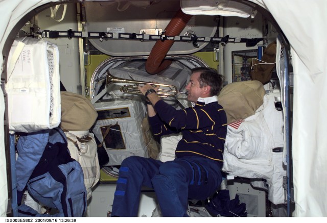 Astronaut Frank L. Culbertson, Jr., Expedition Three mission commander, takes a brief timeout from a busy day to play his trumpet in the Quest Airlock on the International Space Station (ISS). This image was taken with a digital still camera.