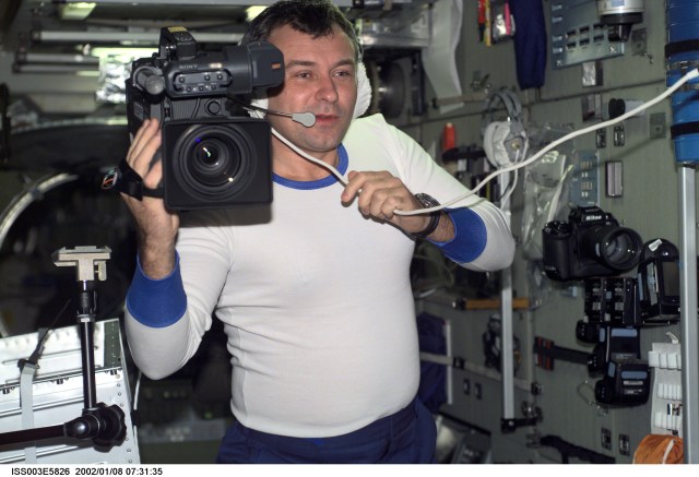 Cosmonaut Vladimir N. Dezhurov, Expedition Three flight engineer representing Rosaviakosmos, works with camera equipment in the Zvezda Service Module on the International Space Station (ISS). This image was taken with a digital still camera.